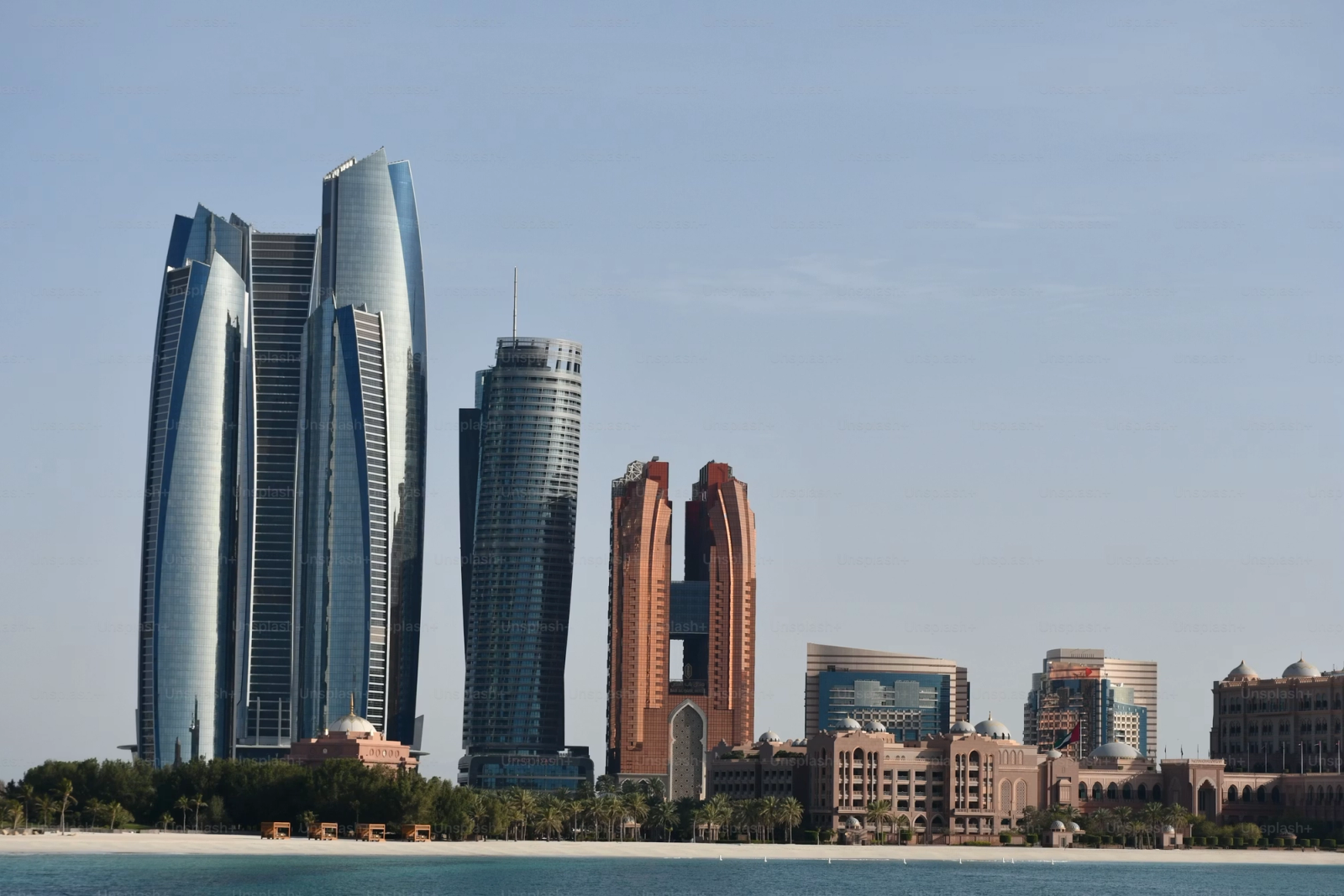 A waterfront skyline with a cluster of curved glass towers