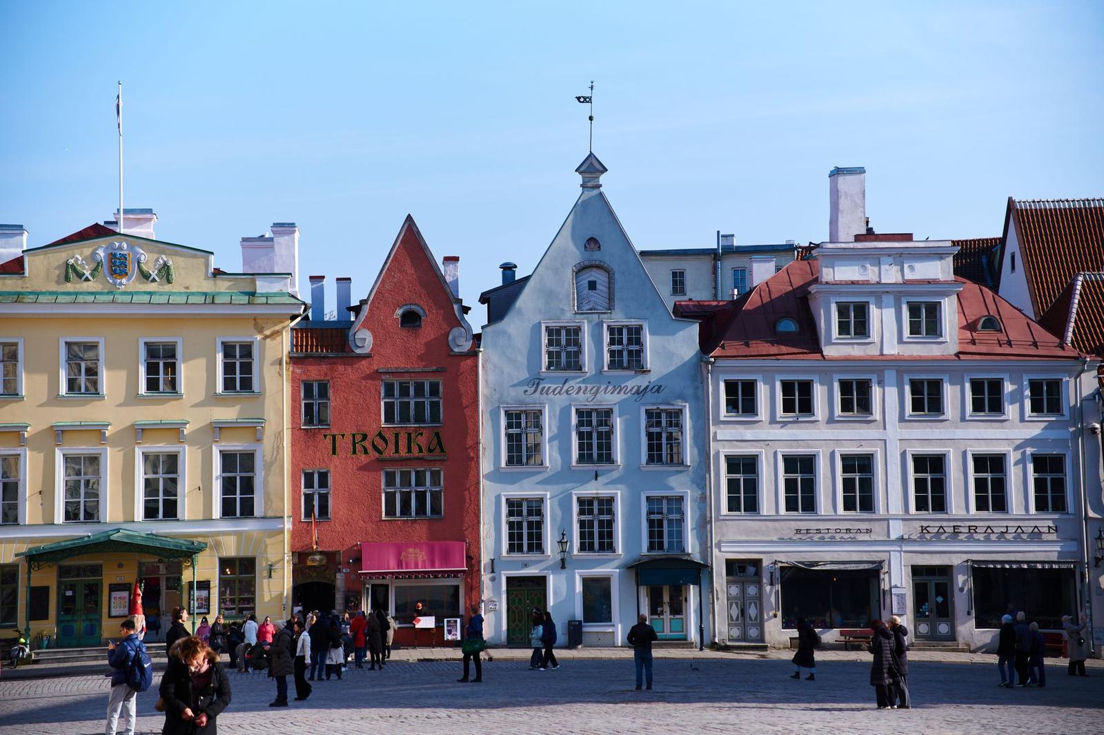 A colourful row of gabled old-town buildings around a cobblestone square with strolling visitors