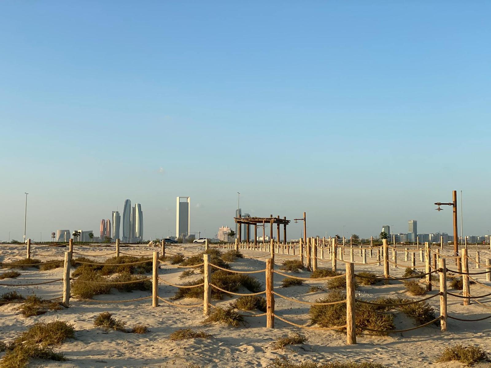 Roped beach path leading toward a distant desert skyline