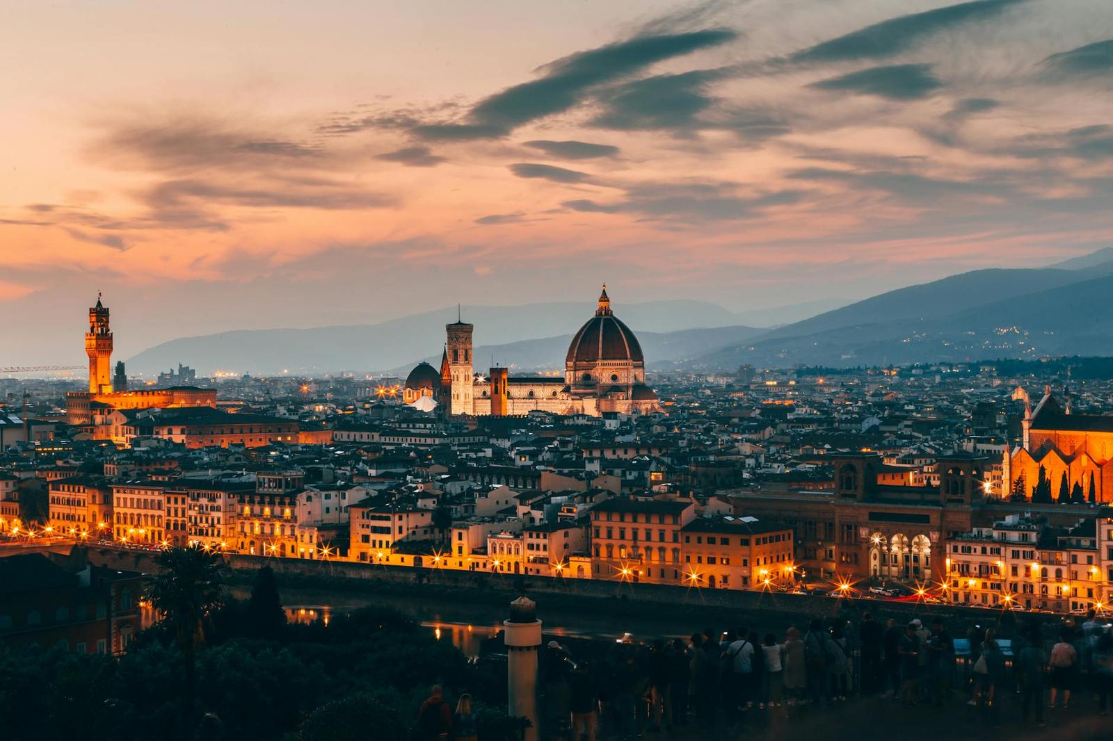 A historic city skyline with a large dome lit at dusk
