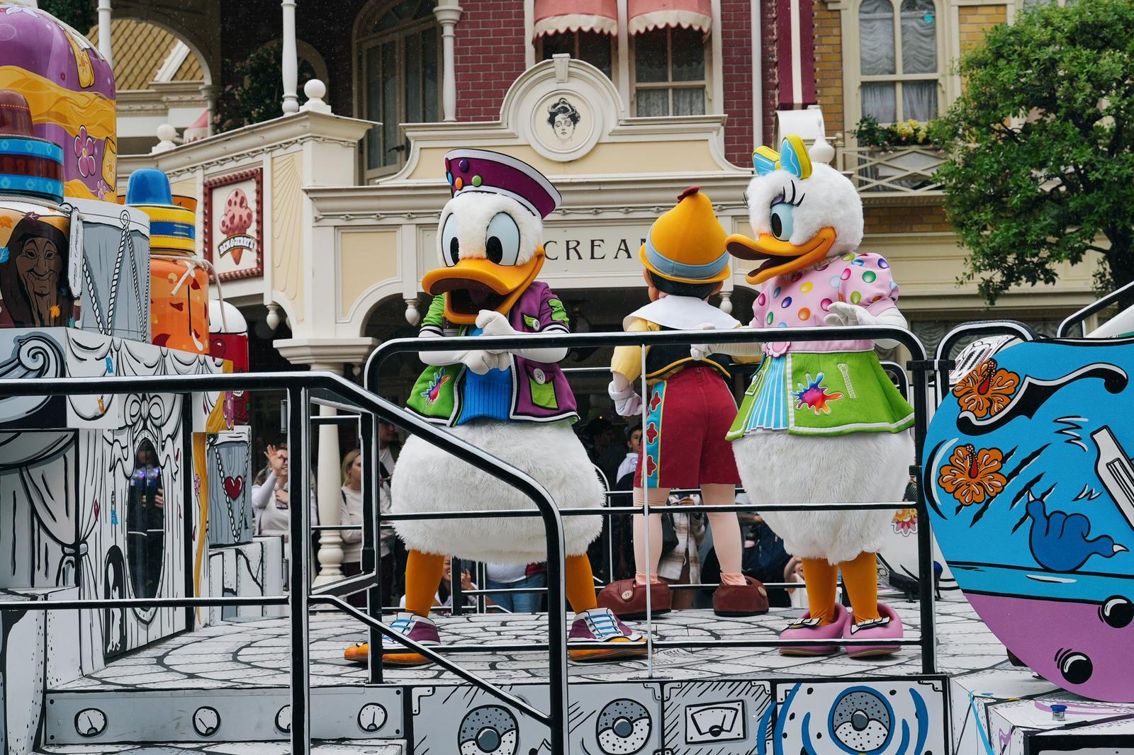 Duck-costumed parade performers dancing atop a colourful float