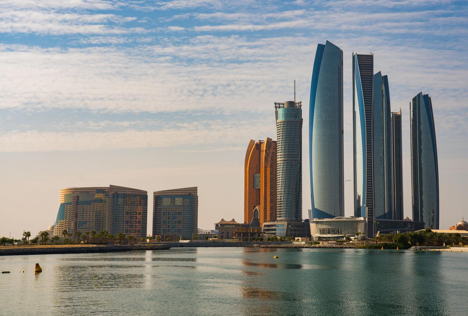 Waterfront skyline of curved glass towers beside a lagoon