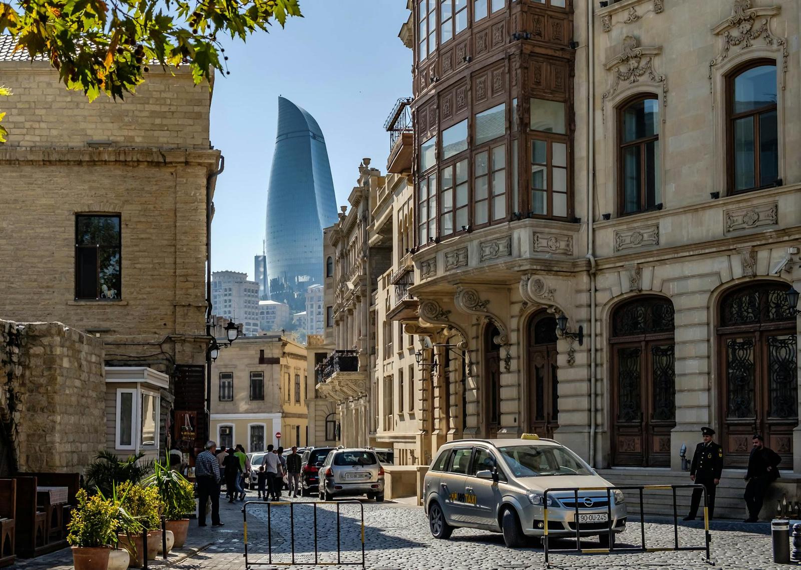 An old-town cobblestone street with a modern skyscraper rising beyond ornate facades