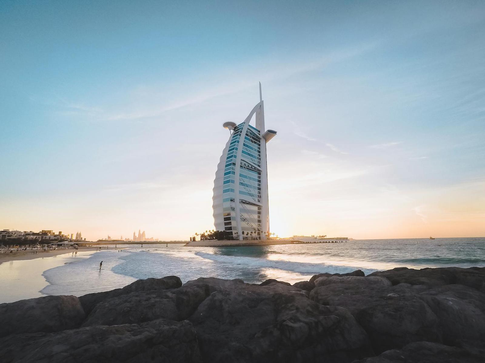 Low angle of Burj Al Arab located on sandy coast of Dubai against cloudless sundown sky