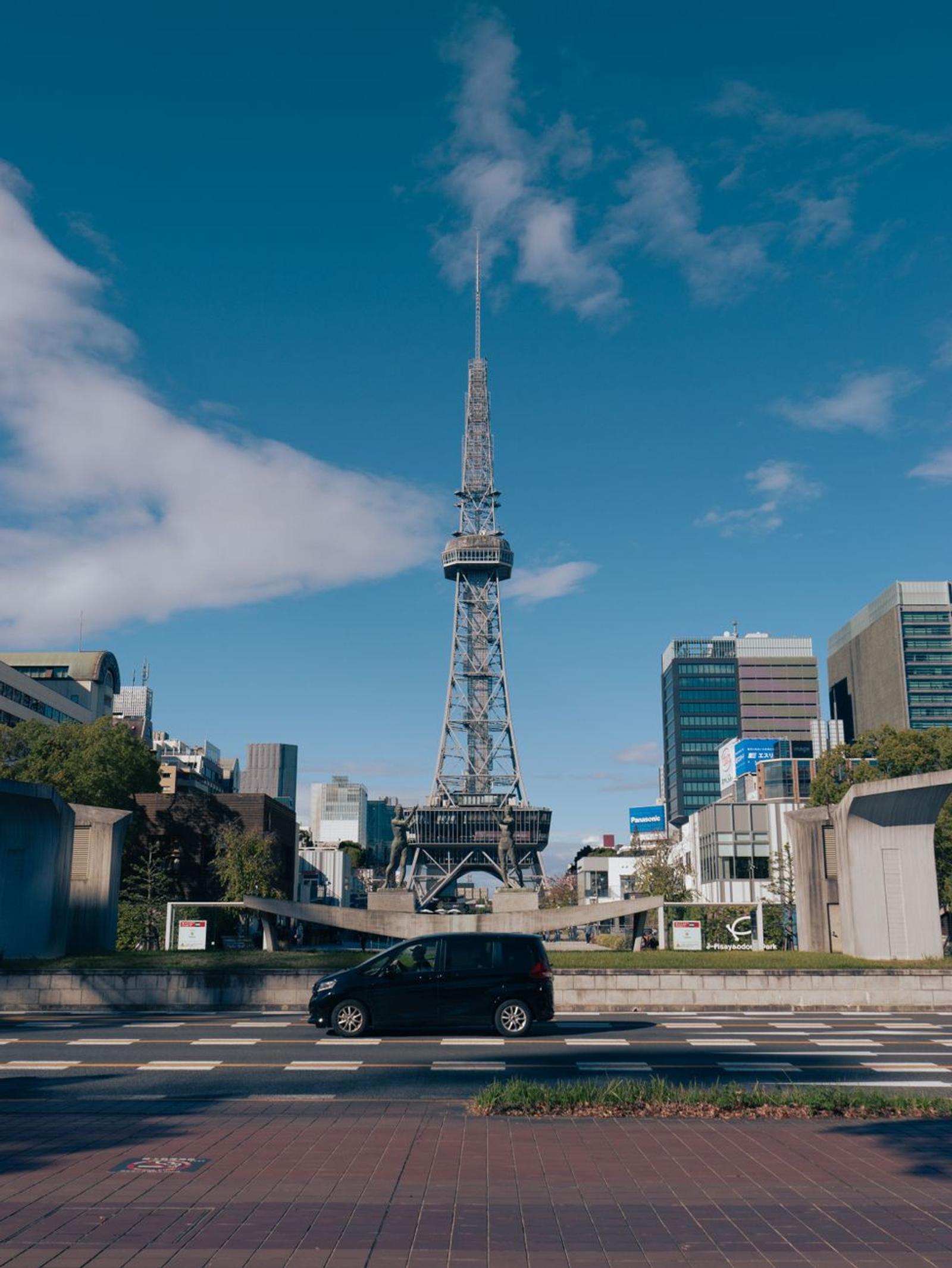 A view of Nagoya TV Tower surrounded by urban buildings under a clear blue sky