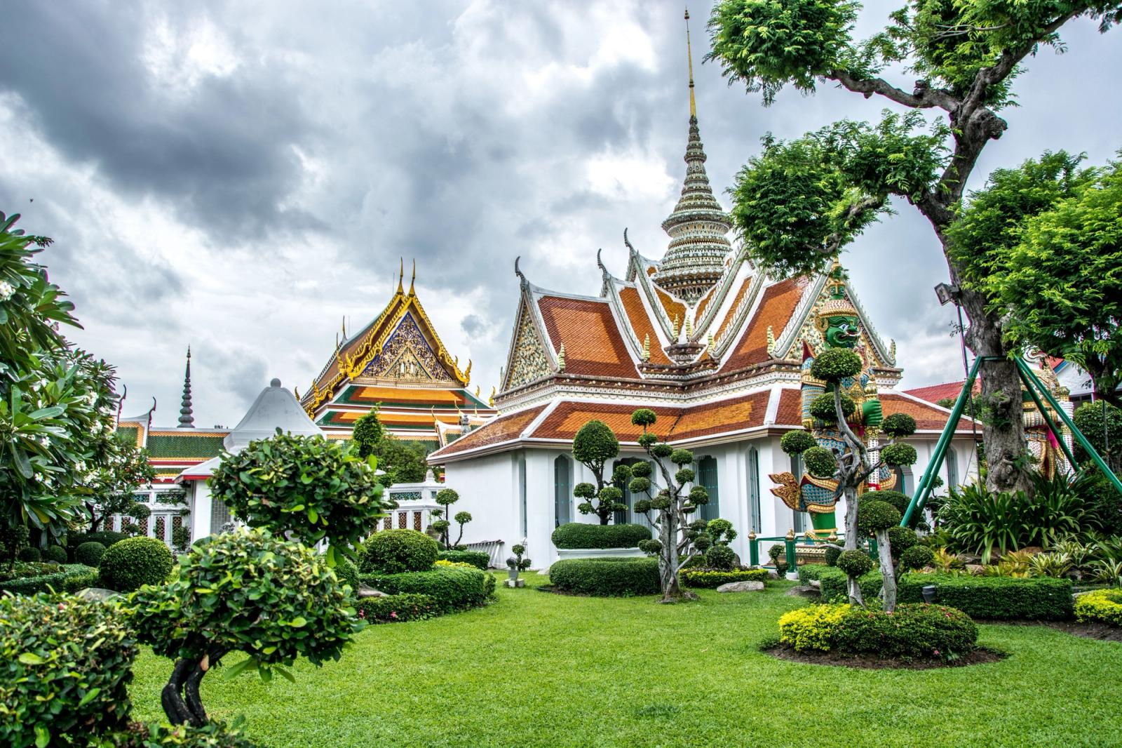 An ornate temple pavilion with tiered roofs set among manicured garden topiary