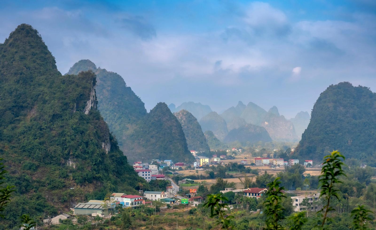 Jagged karst peaks rising above a misty village valley