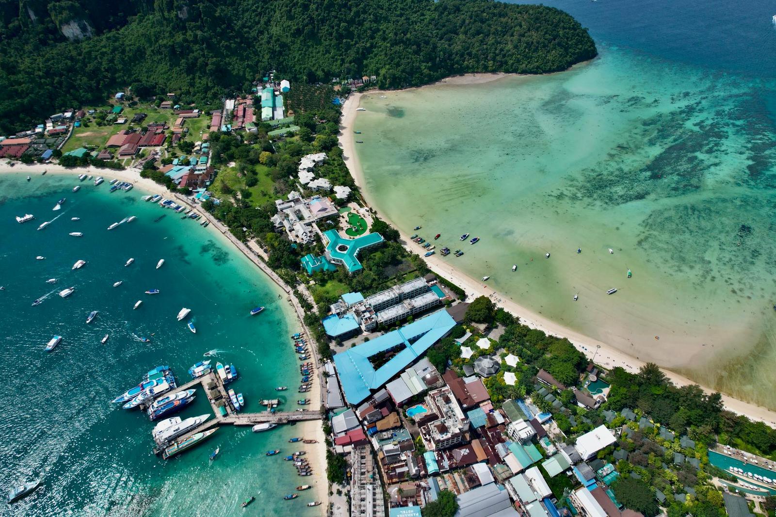 Aerial view of a resort complex along a beach cove with boats moored offshore