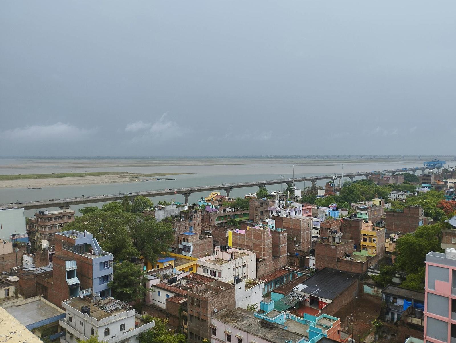 Aerial view of a riverside town of low buildings meeting a wide sandbank under grey sky