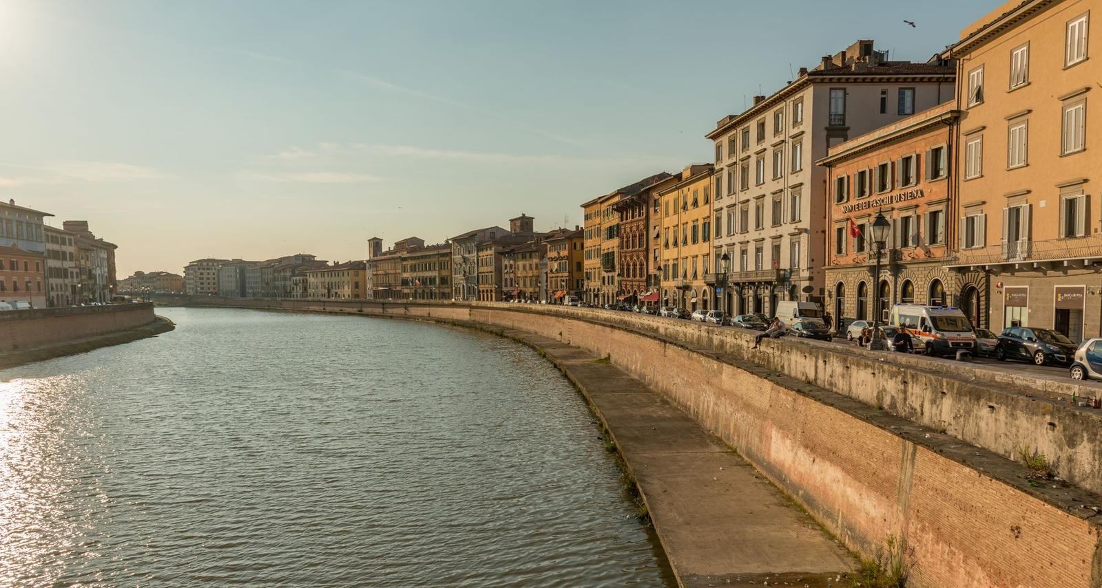 Riverside street lined with historic buildings glowing at golden hour