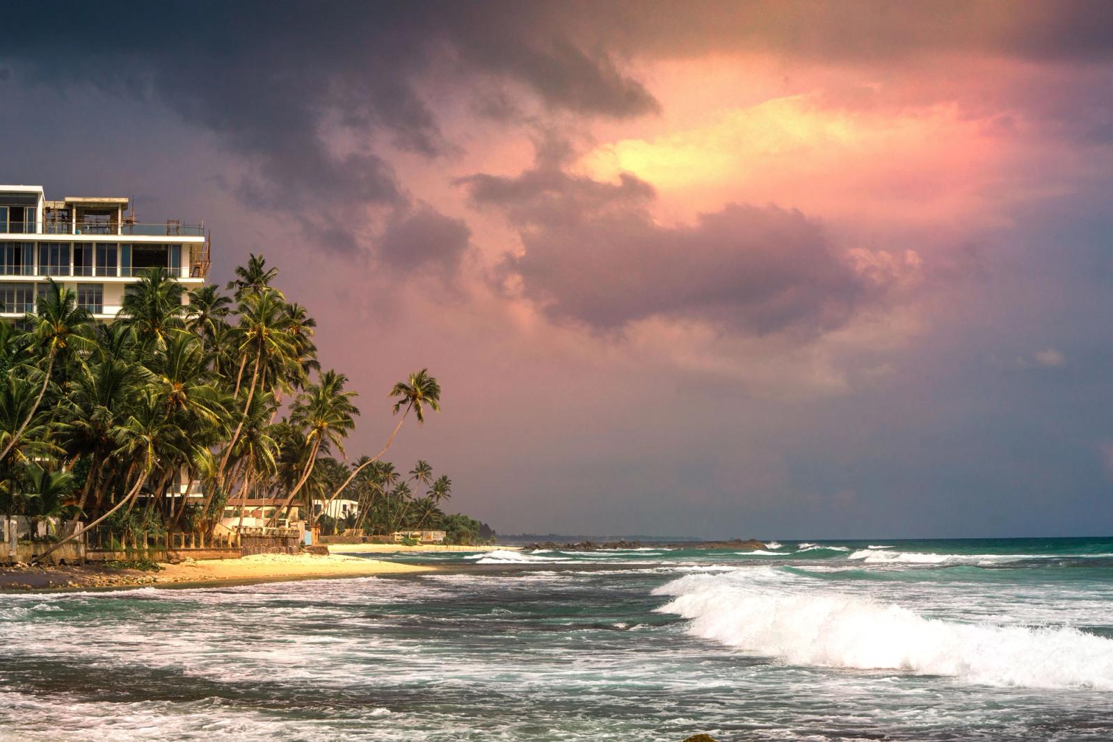 Stunning sunset at Unawatuna Beach, Sri Lanka, with palm trees and ocean waves