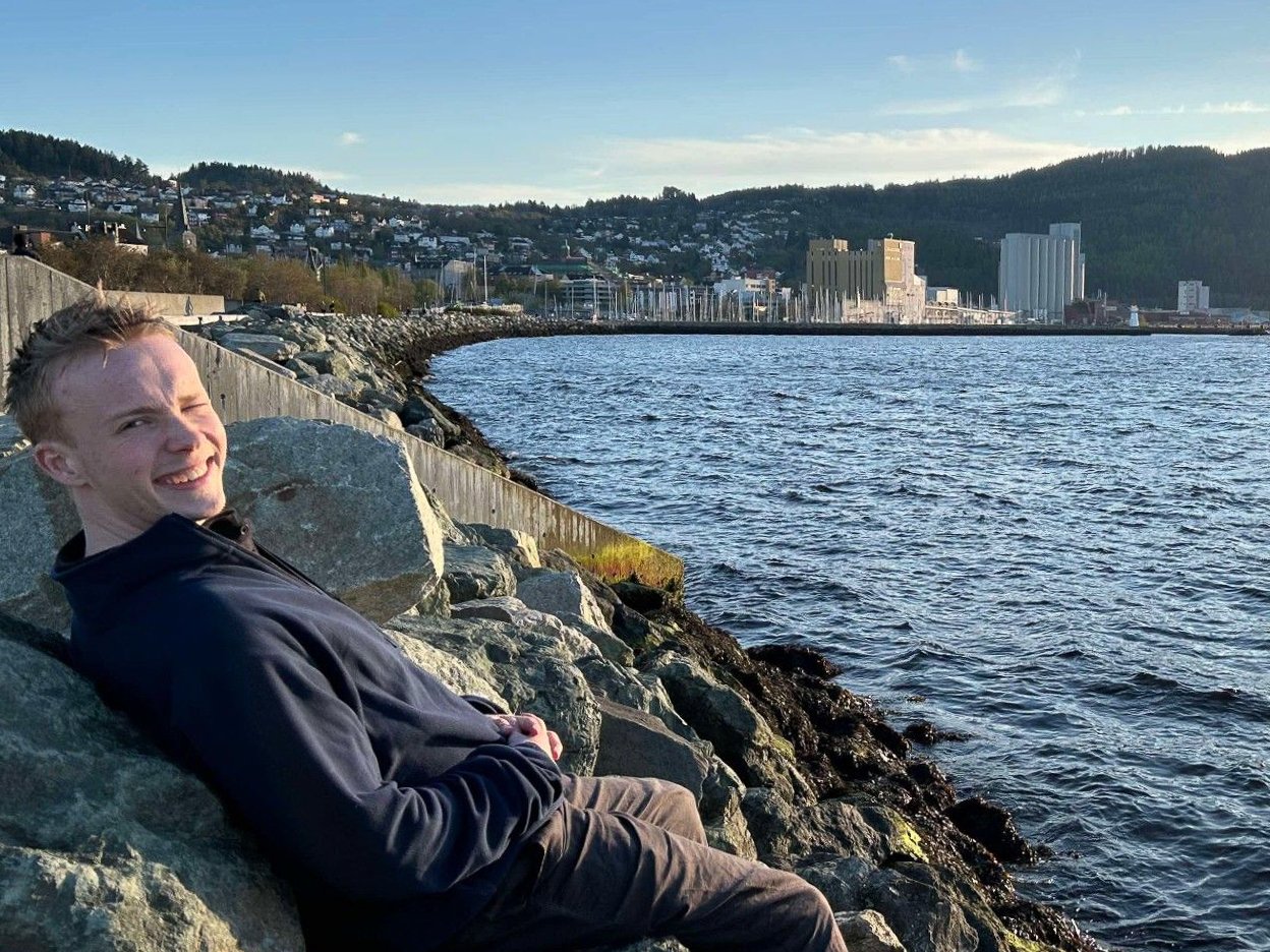En ung mann som smiler mot kamera i Trondheim ved Ila.
