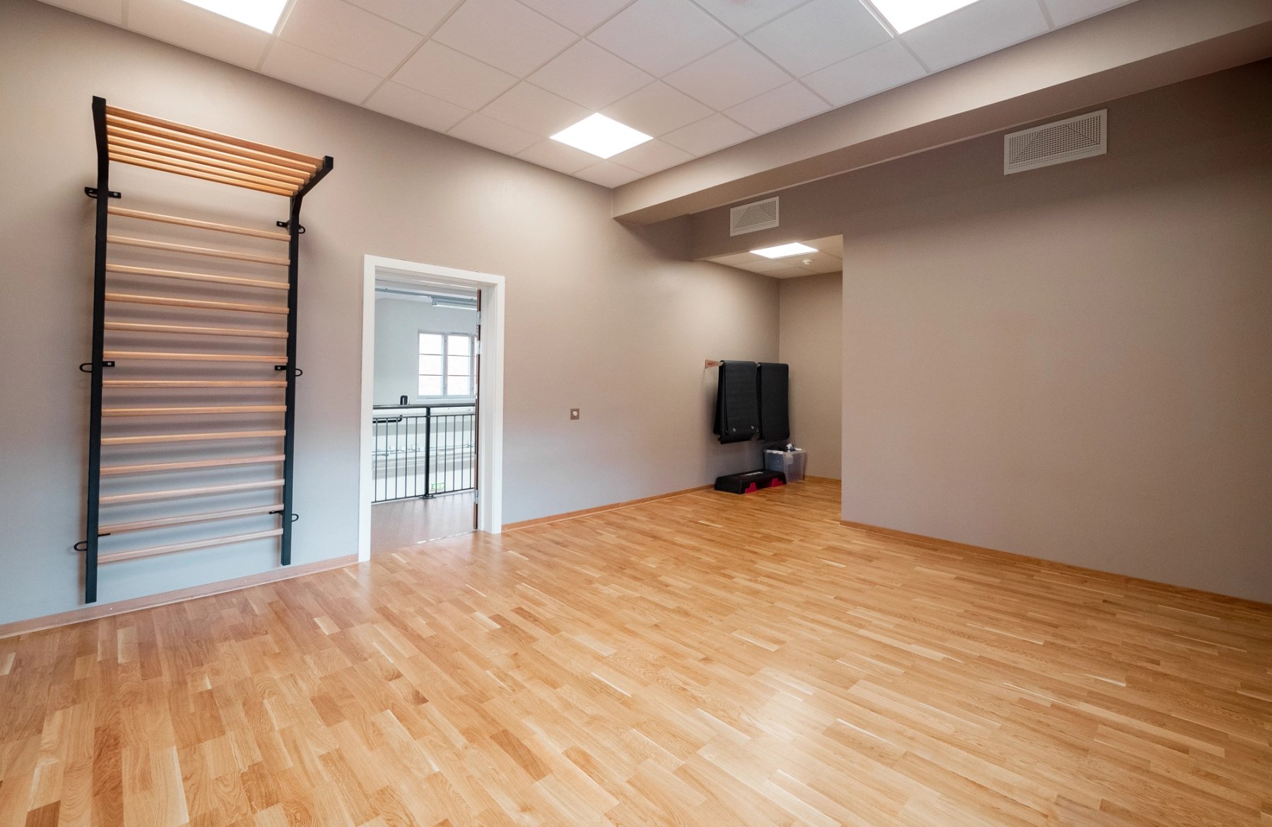 En liten gruppesal med parkett på gulvet og en seksjon med ribbevegg. 