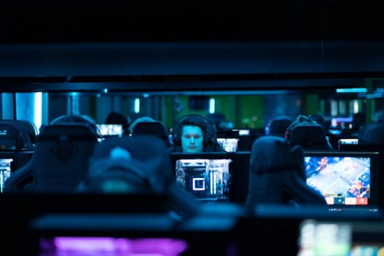 Et mørkt rom der flere mennesker ser på hver sin dataskjerm, med headset på hodet.