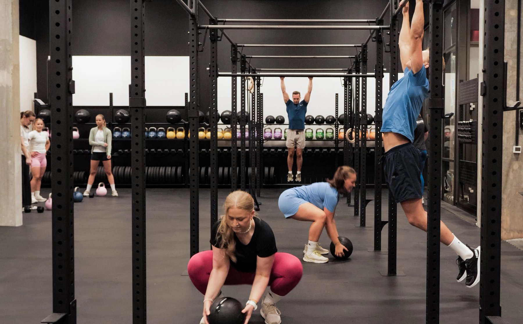 Mennesker som trener funksjonell styrke med slamballer og pullupbarer. 