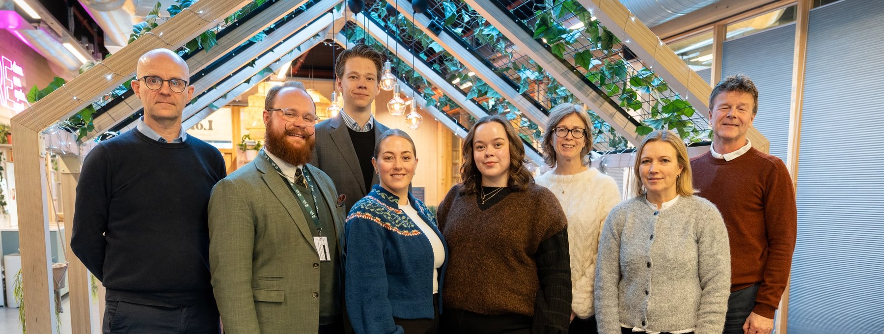 The Board of Sit gathered in an indoor shared space. Eight board members stand in a row, facing the camera.