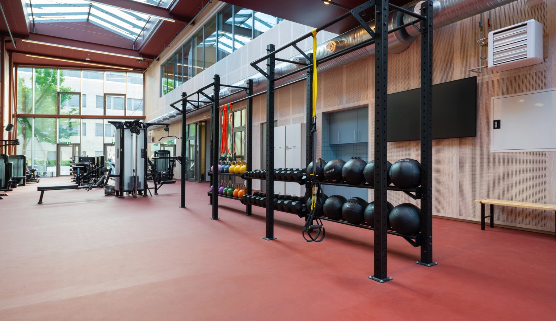 Område for funksjonell trening; en rigg med tversgående stenger for pullups, og utstyr som medisinballer, manualer og kettlebells.