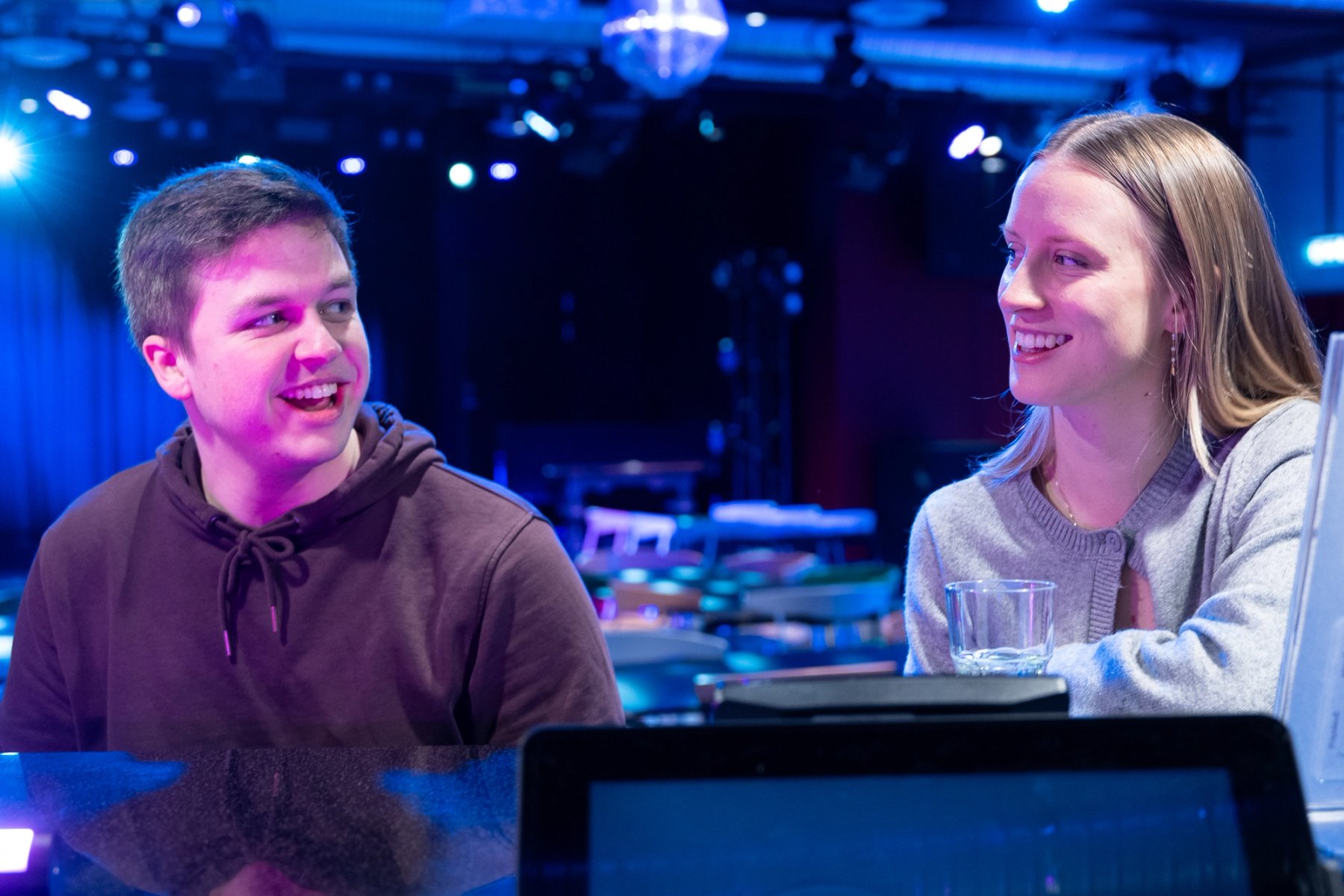 To studenter sitter og smiler til hverandre ved en bar
