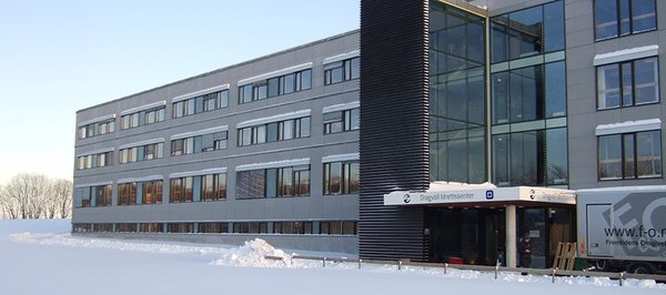 Fasaden til Dragvoll idrettssenter og tilhørende kontorer for NTNU. Bygget er grått med mange vinduer. 