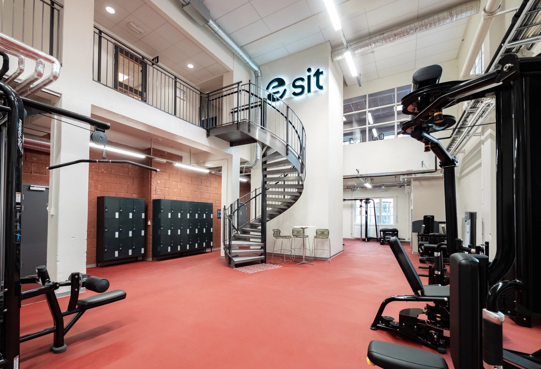 Et område i treningssenteret med garderobeskap og en trapp opp til gruppesal.