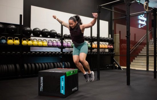 En jente som hopper sidelengs opp på en knehøy kasse. 