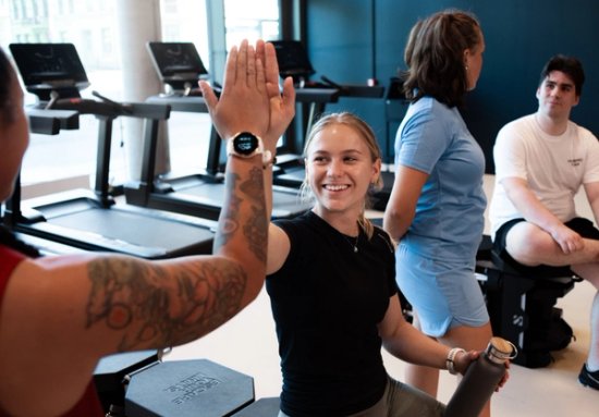 To jenter so gir hverandre en high five inne i et treningssenter. 