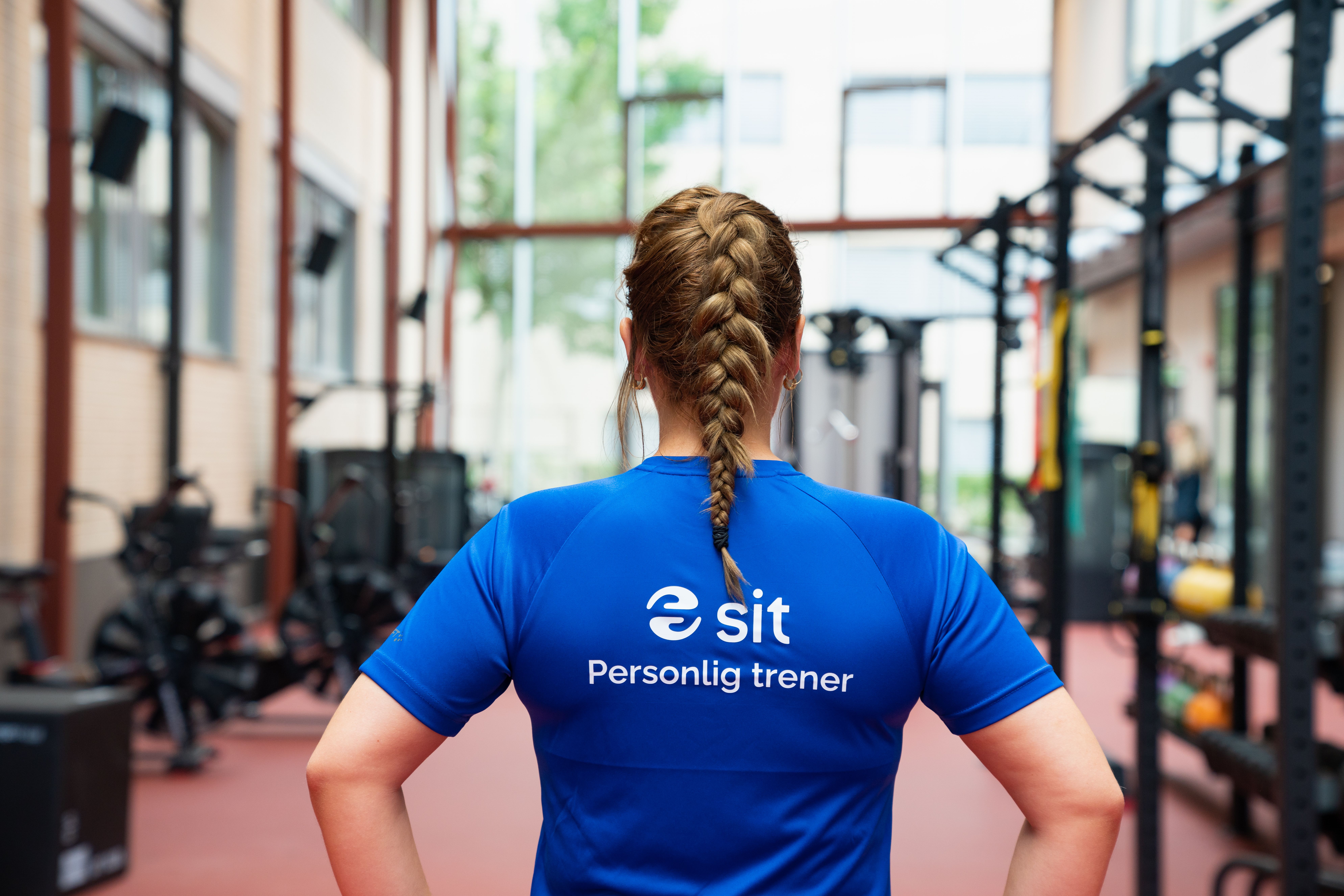 Personal trainer wearing a blue Sit t-shirt standing in a gym.
