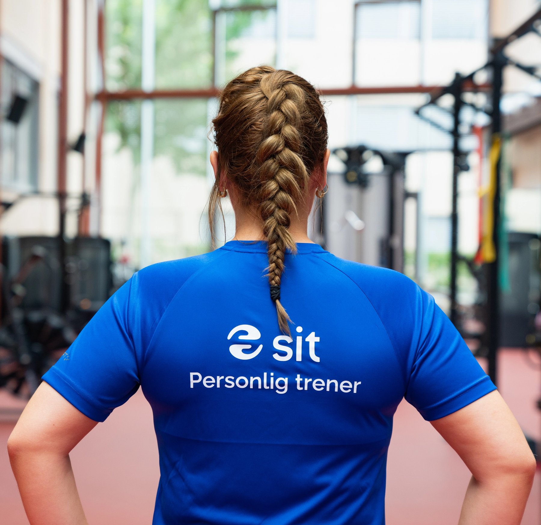 Personal trainer wearing a blue Sit t-shirt standing in a gym.