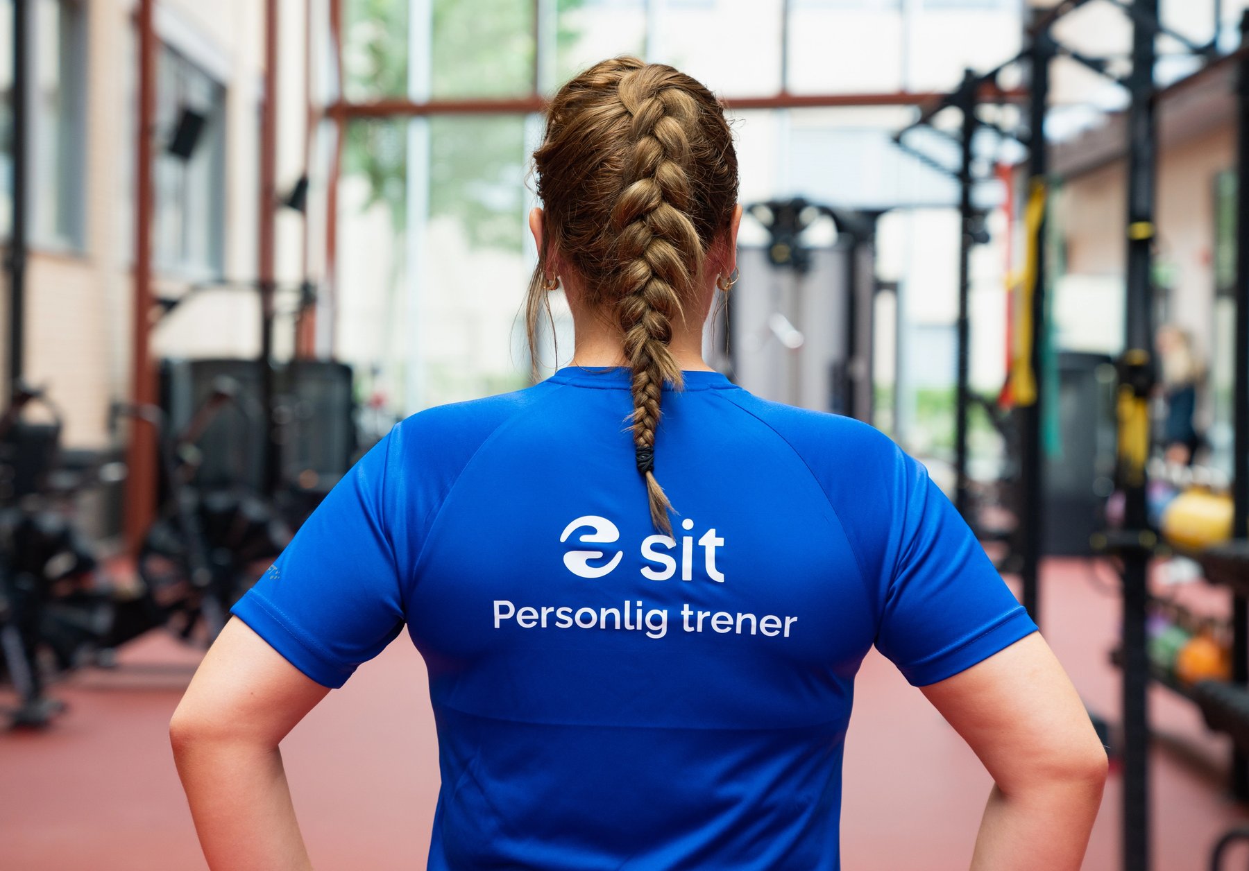 Personlig trener med Sit-logo står i treningssal.