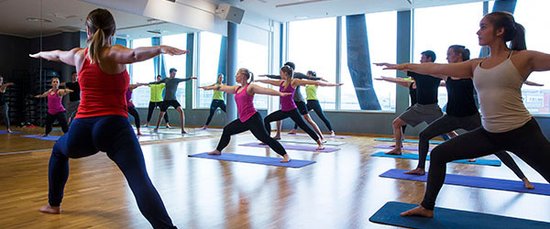 Mennesker som står i en krigerposisjon på yogamatter. 