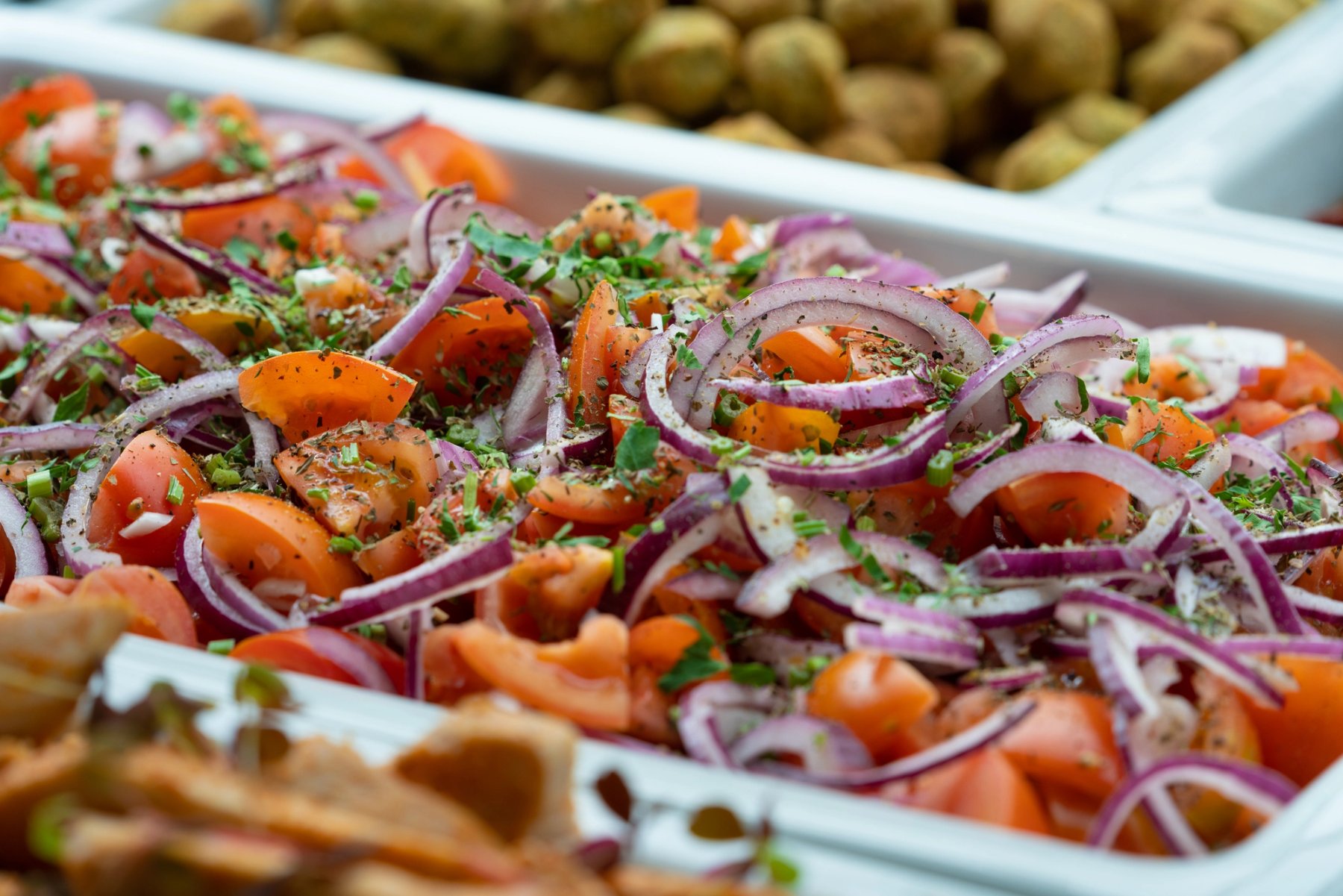 Salatbar med tomater, rødløk og urter i Sits kantine.