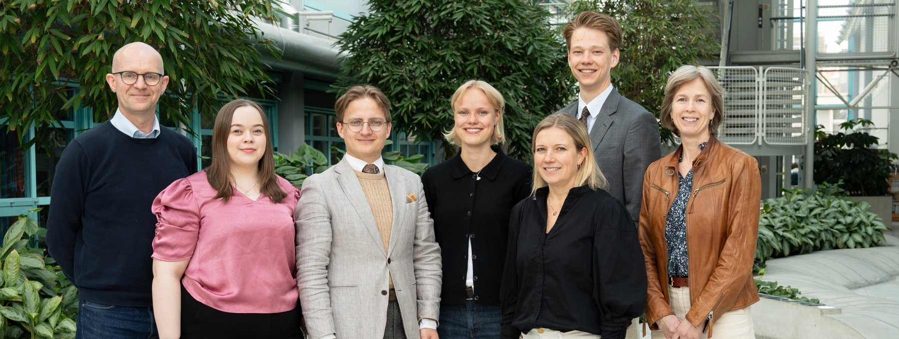 The Board of Sit gathered in an indoor shared space. Eight board members stand in a row, facing the camera.