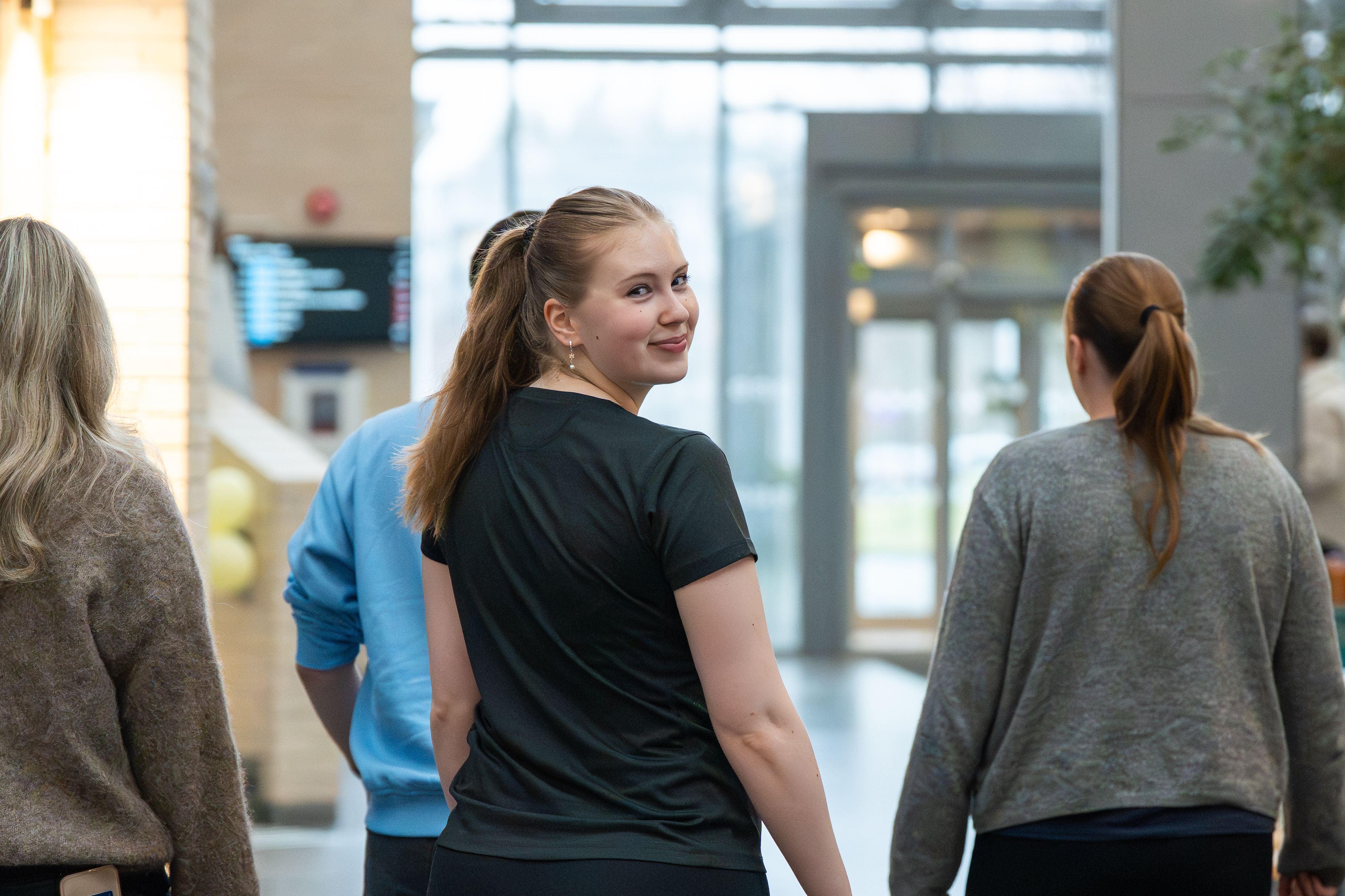 Studenter går sammen gjennom et lyst og åpent innendørsområde i et NTNU-bygg.