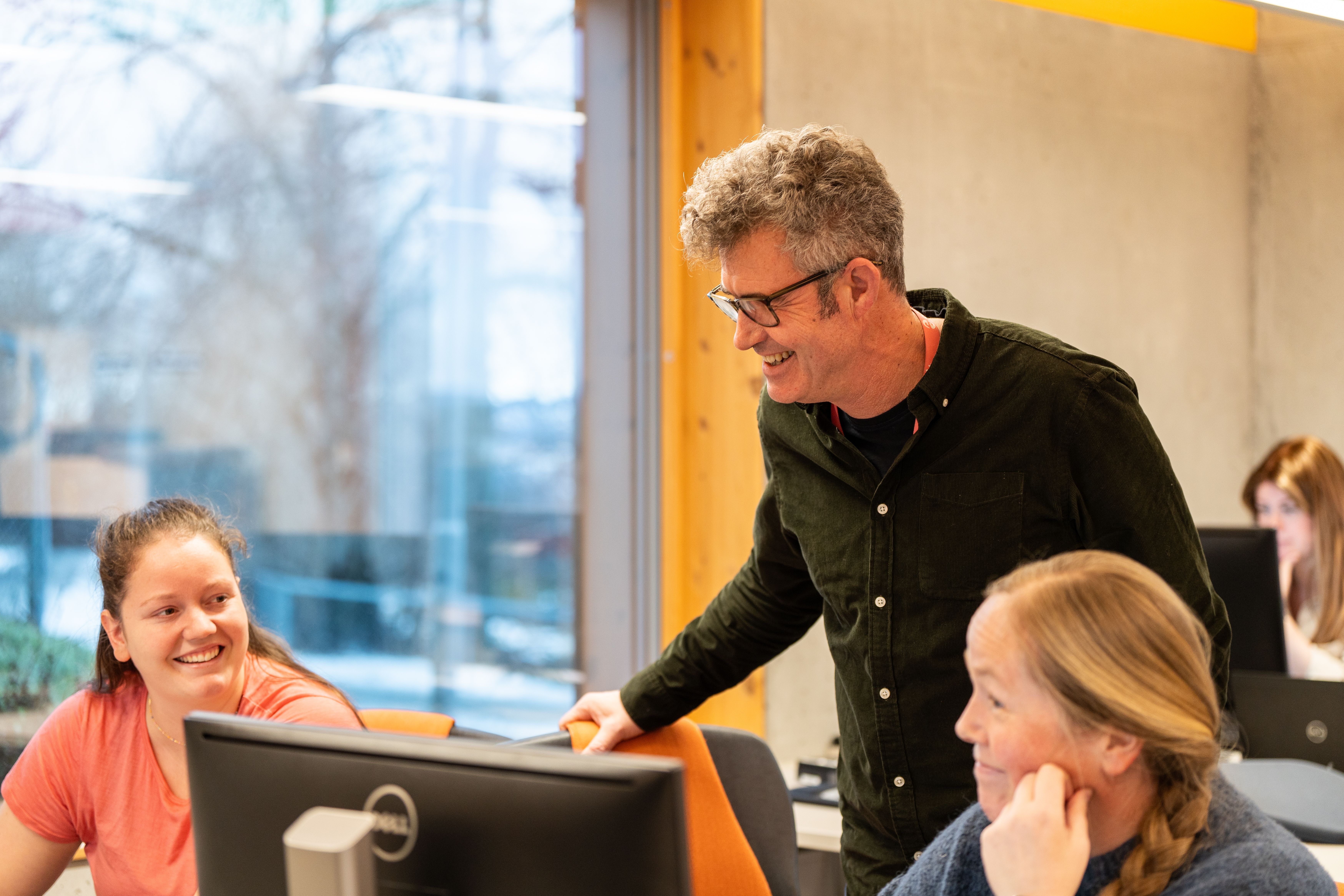 Ansatte i Sit i samtale rundt en PC på kontorarbeidsplass.