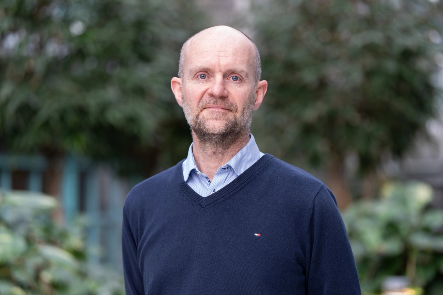 Espen Munkvik, ansattrepresentant, Sit, smiler mot kamera i et grønt utemiljø.