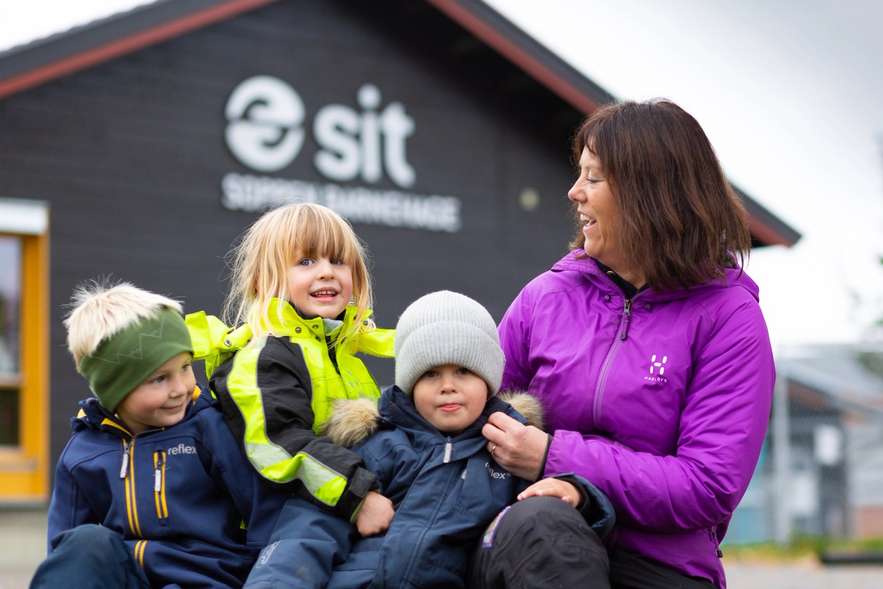 Foto av tre barn og en barnehageansatt utenfor Soppen studentbarnehage på Gjøvik. Alle har på seg ytterklær.