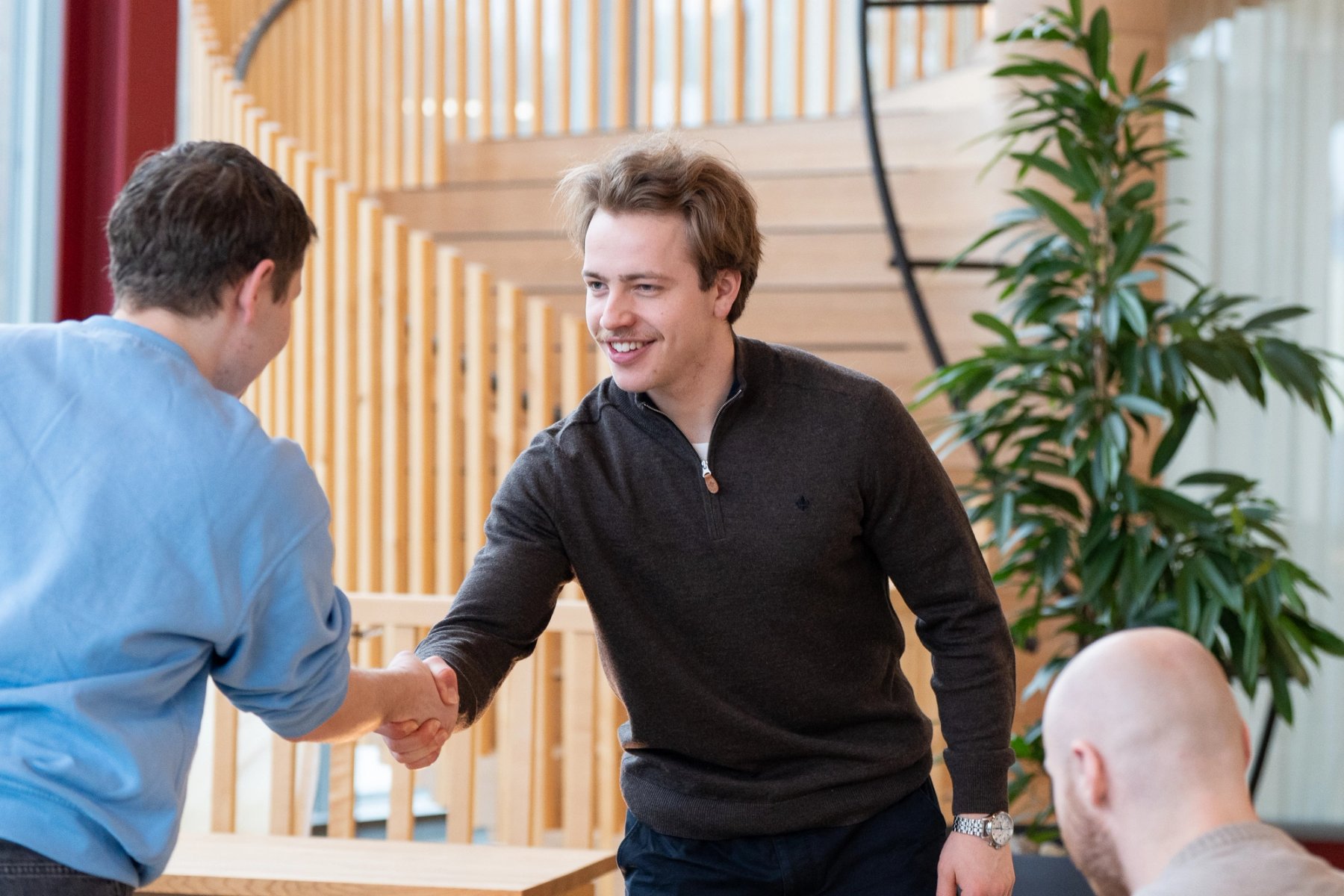 En mannlig student håndhilser på en annen student ved campus Ålesund, ser han i øynene og smiler.