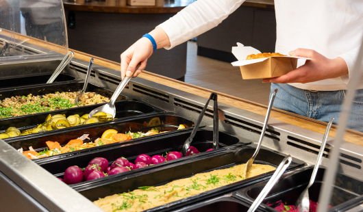 Person som forsyner seg av salatbuffeten i kantina på Dragvoll