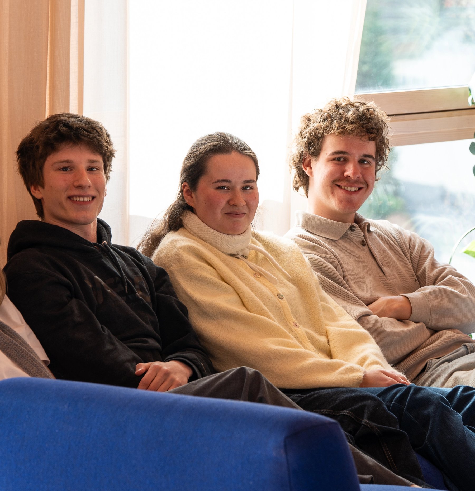 ire studenter sitter sammen i sofa i et lyst fellesområde i studentbolig.