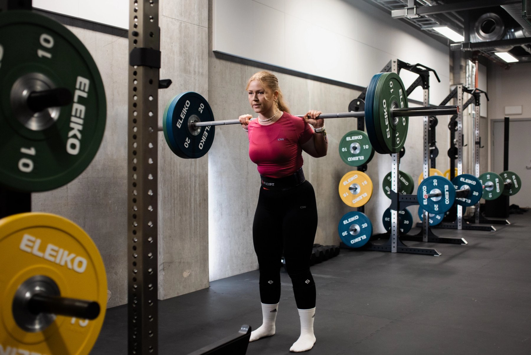 En jente som tar knebøy med vektstang og skiver fra Eleiko.