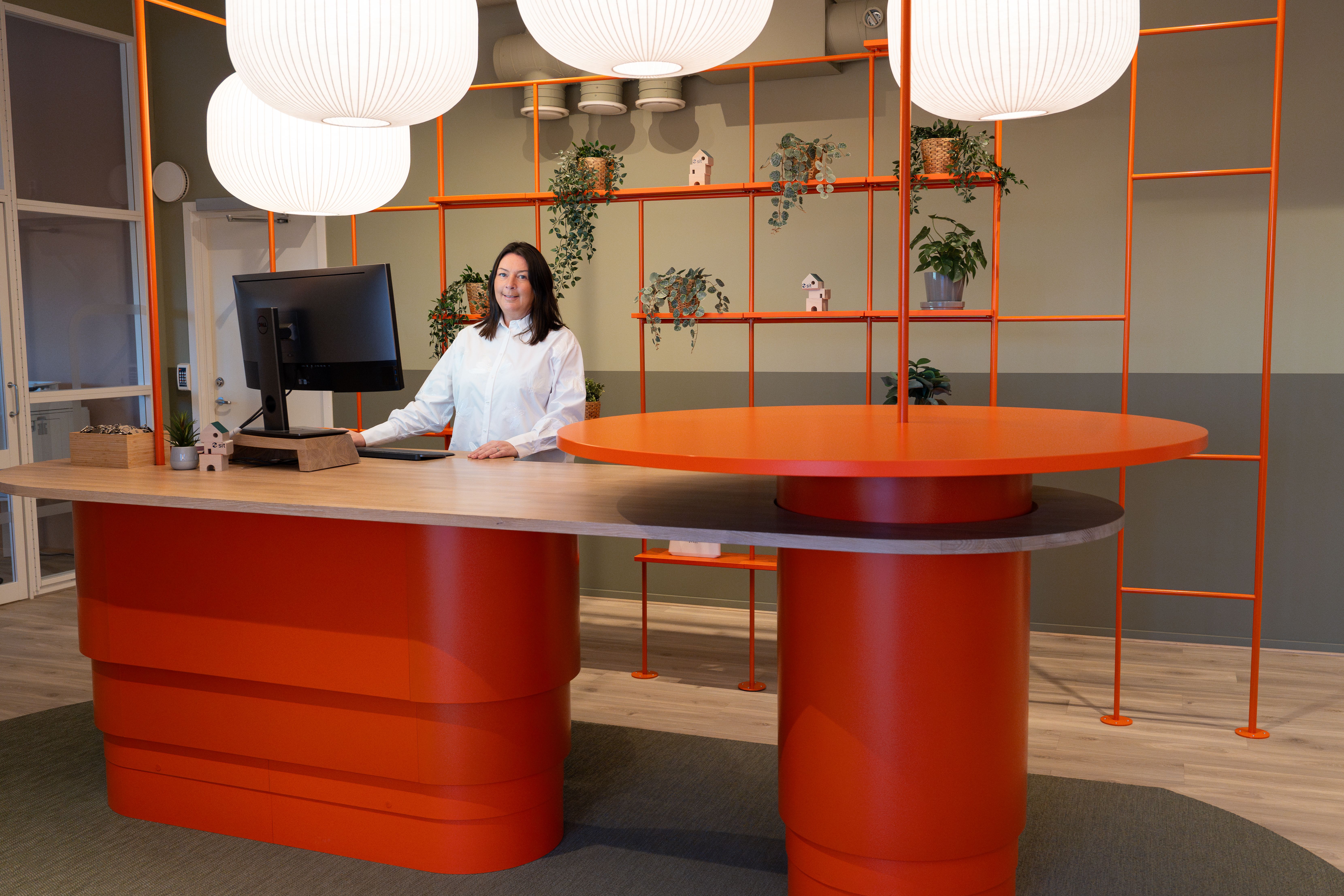 Resepsjonen på Sit bolig med medarbeider bak skranke i moderne lokaler.