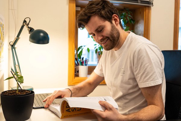 A student reading a book studying in his student apartment in Teknobyen. 