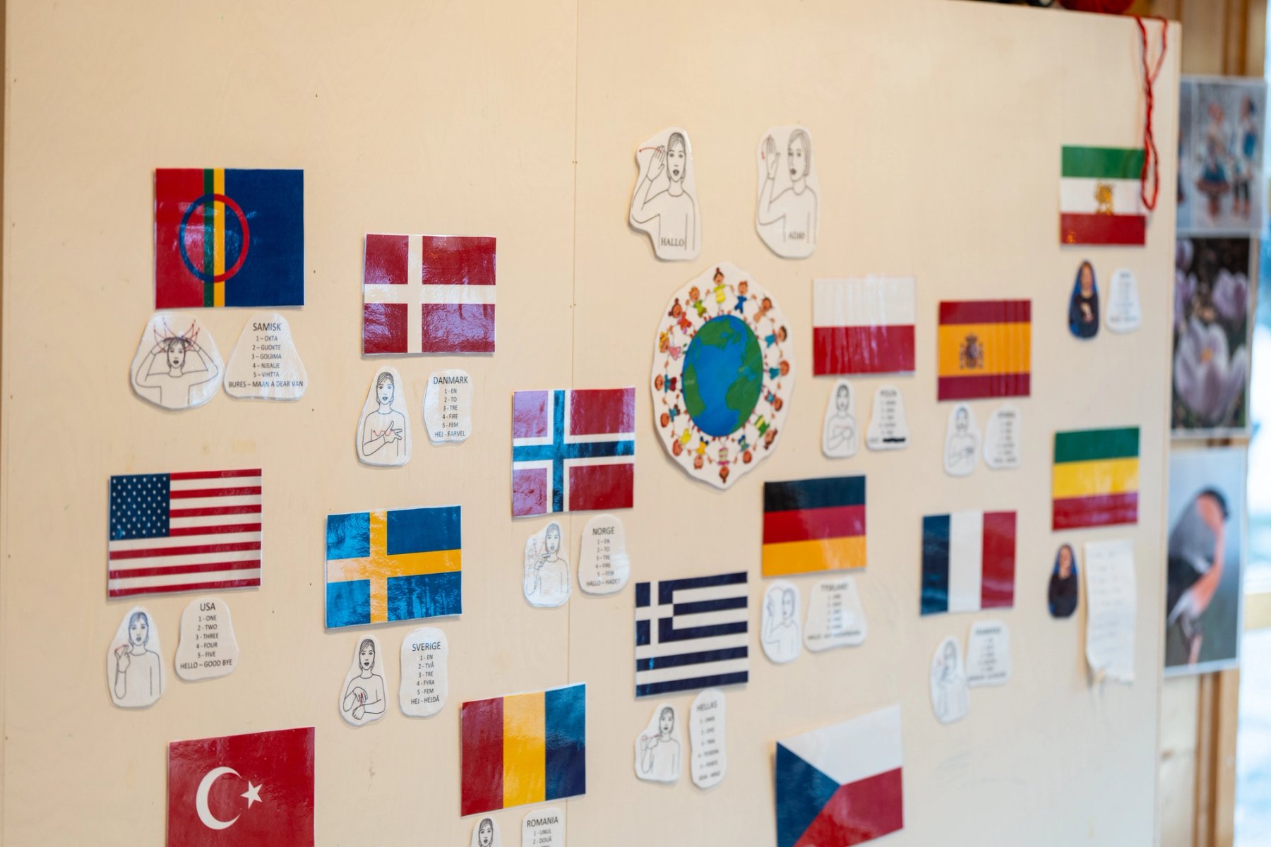 Diversity and inclusion are central in the kindergarten. The wall is decorated with flags from different countries and simple sign language illustrations.