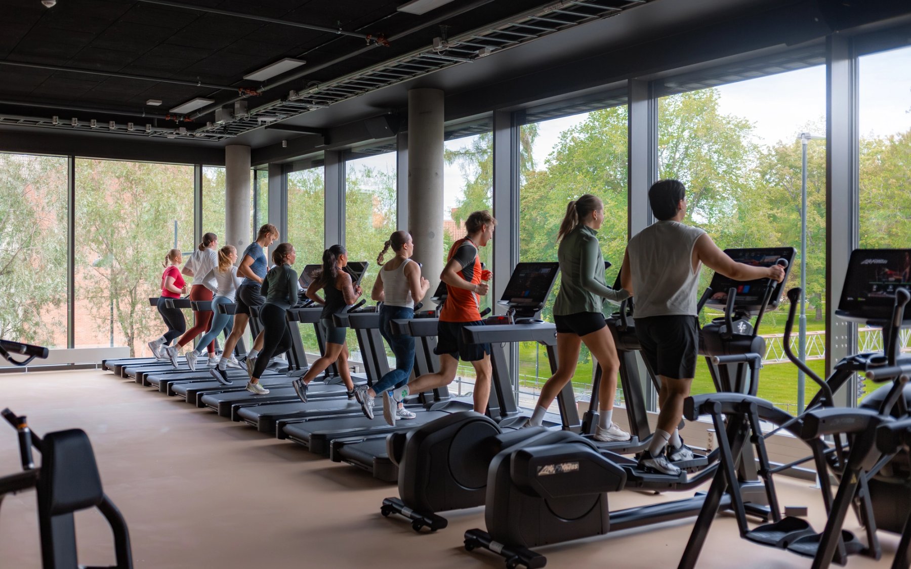 Folk som løper på tredemøller og bruker ellipsemaskin på et treningssenter.