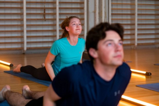 To personer som ligger på magen på treningsmatter og ser skrått oppover. 