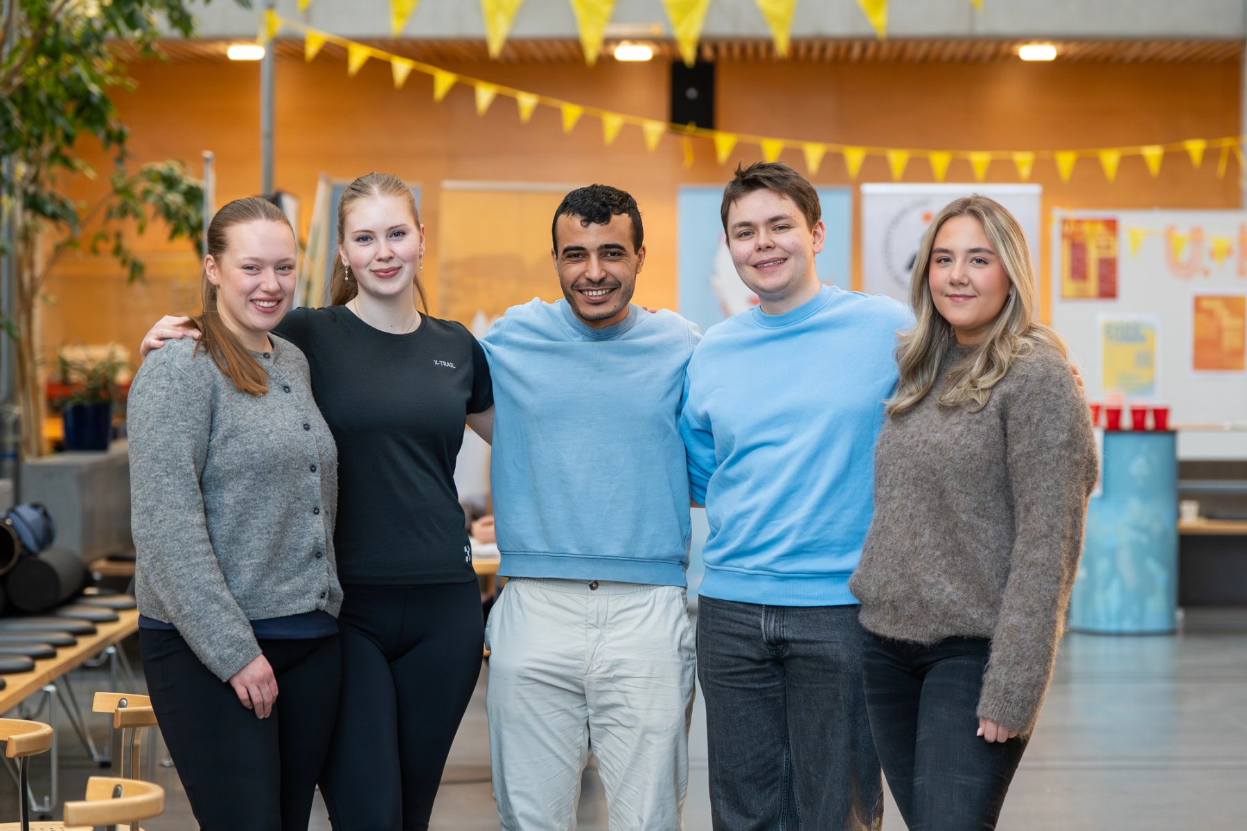 Fire studenter som går på campus i Ålesund, en av dem, en kvinnelig student, snur seg mot kamera og smiler.
