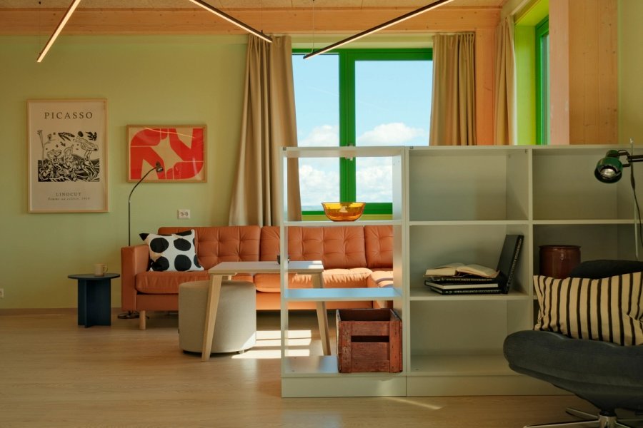 Lys og moderne studentbolig med sofa, bord, bokhylle og store vinduer.