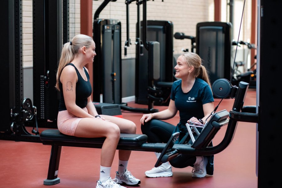 Personal trainer talking to a student in a seated cable machine.