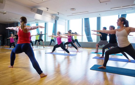 Mennesker som står i en krigerposisjon på yogamatter. 
