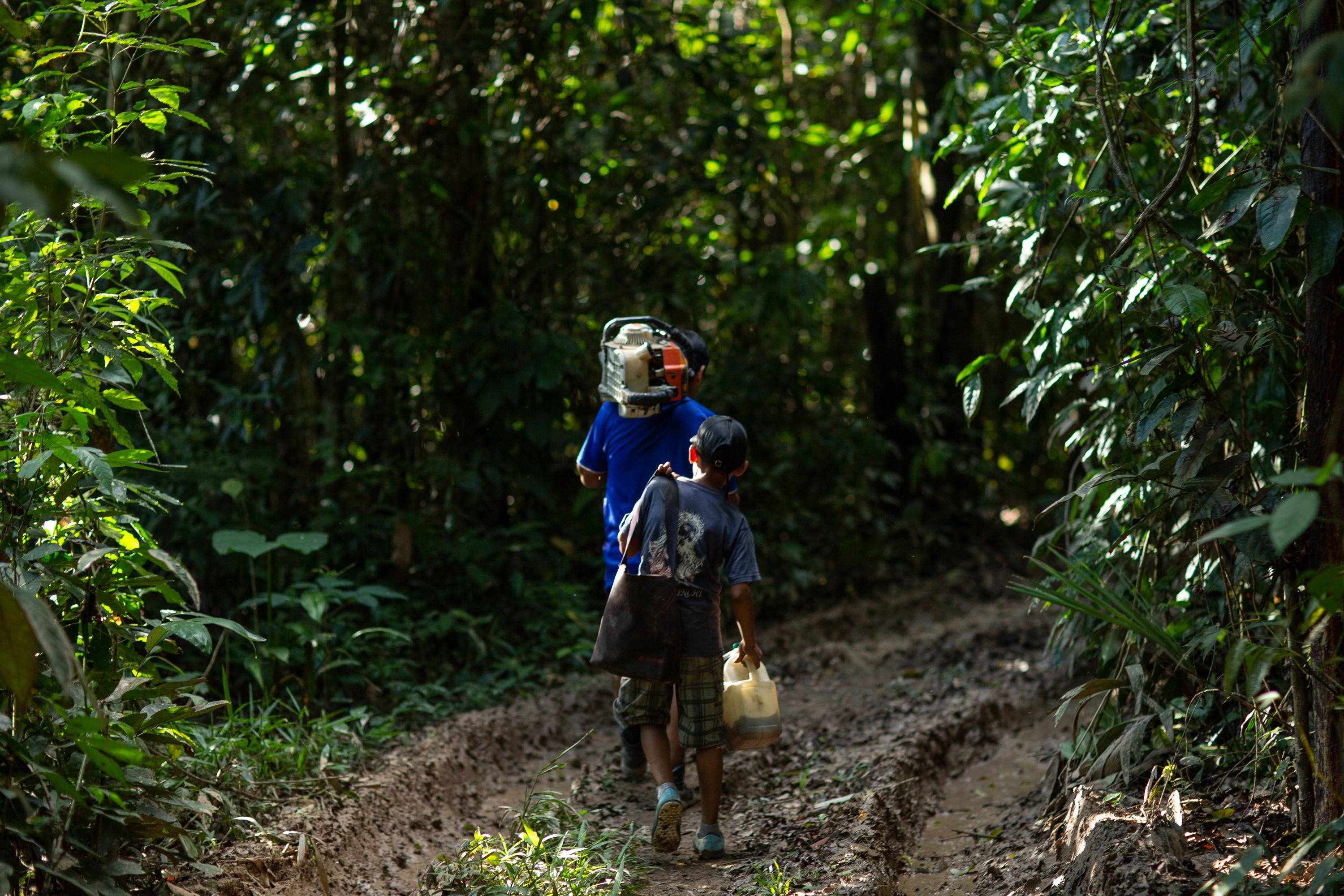 A man and a child carrying chainsaw and equipment.